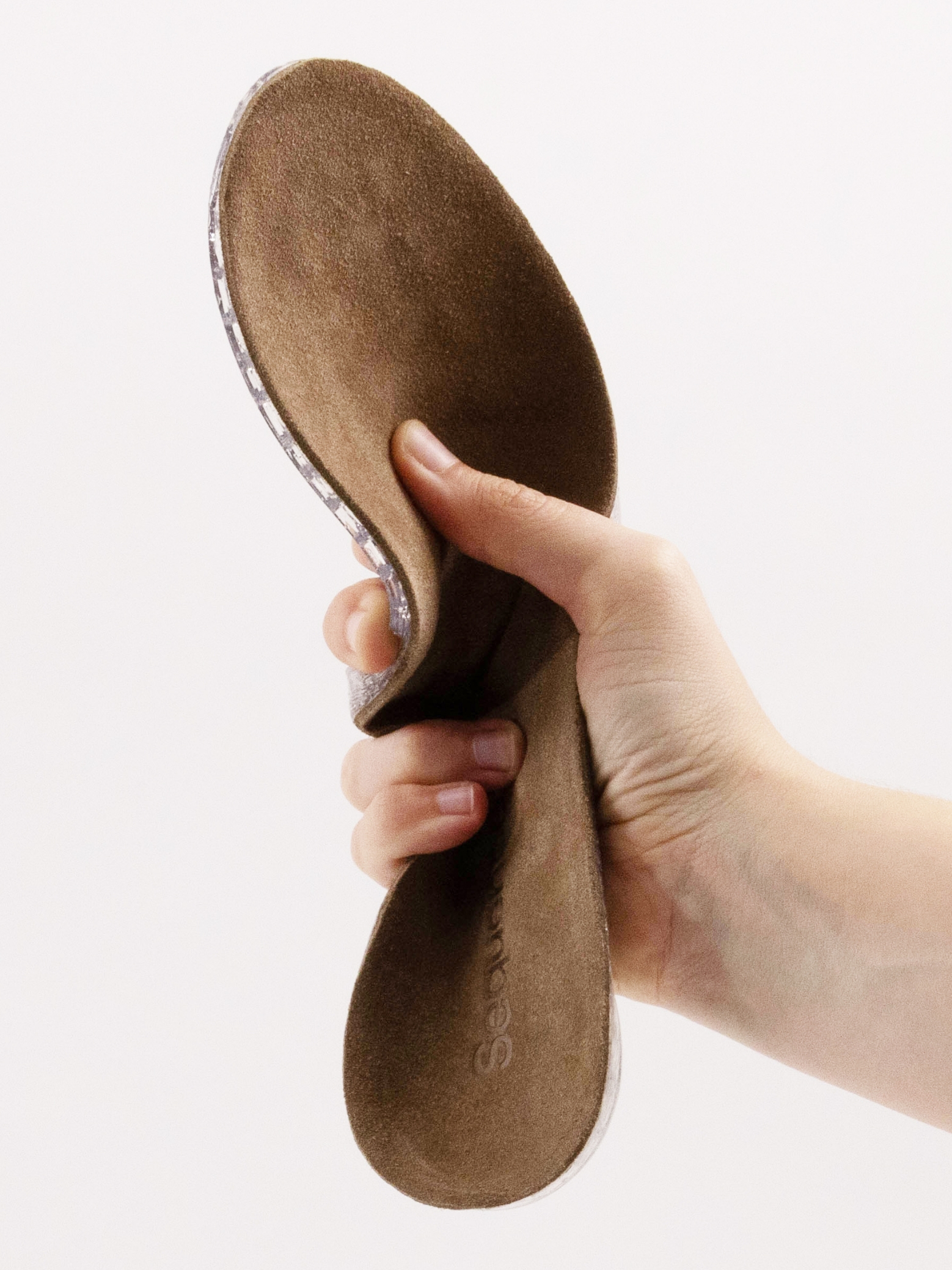 A Sequence insole flexed by hand, showing the printed silicone lattice at its edge